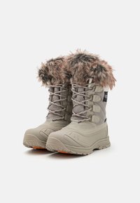 Lys beige vanntette støvler med teksturert overdel, pelsfôret krage og oransje detalj på sålen. Har snøring for sikker passform.