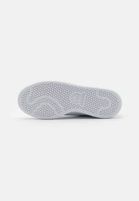 Semelle de sneaker blanche avec un motif texturé hexagonal. Présente un design de vague légèrement surélevé et un logo bien visible. Surface propre et lisse.