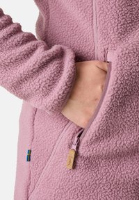 Fleece jack in zacht roze met een textuur oppervlak, ritszak met trekkoordinatie en Zweedse vlag label. Ontwerp bevat getailleerde mouwen.