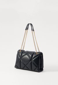 Black quilted leather handbag featuring a gold chain handle and soft, structured design, with detailed stitching and a smooth texture.