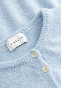 Weiche hellblaue Strickjacke mit geripptem Kragen und zwei weißen Knöpfen an der vorderen Öffnung.