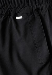 Zwarte elastaine taillebroek met een slim fit, voorzien van een discret zijzak en een klein metalen label met "CECIL" erop genaaid.