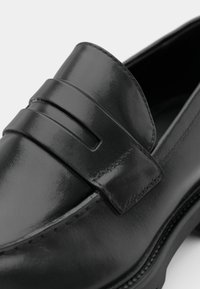 Sorte skinnloafers med en glanset finish, med en teksturert stroppdetalj over vamps og kontrasterende søm langs sålen.