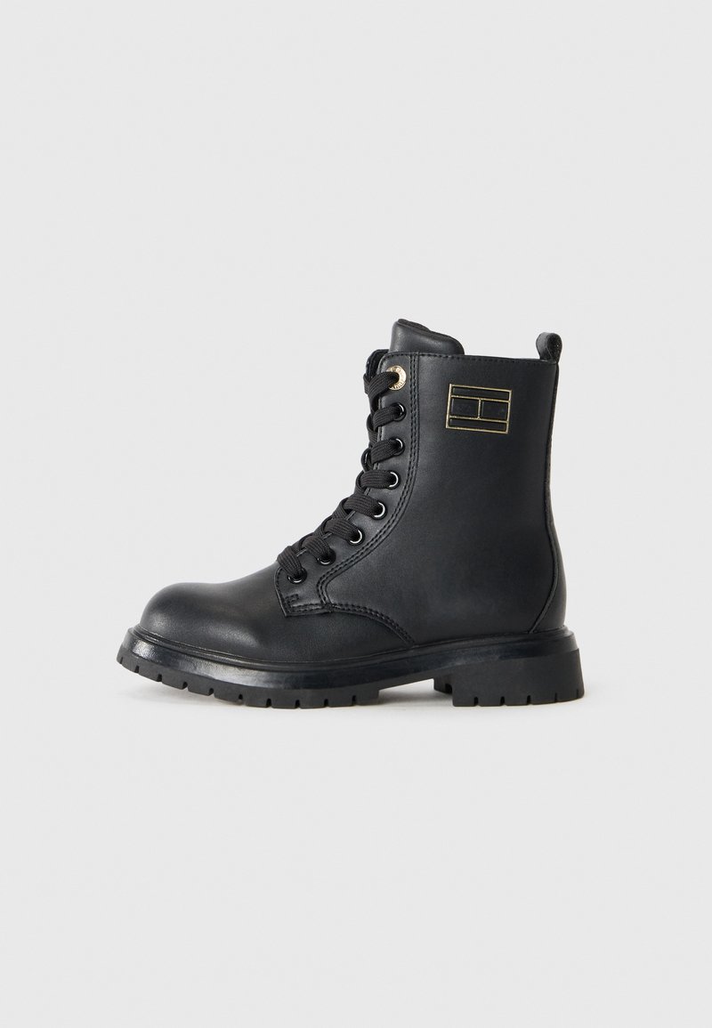 Scarpe stivali alla caviglia in pelle nera con punta tonda, lacci sul davanti, dettagli dorati e suola in gomma. Presentano un logo sul lato e un tallone rinforzato.