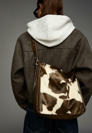 Brown leather shoulder bag with cowhide panel featuring white and brown patches; sleek design with a zipper detail and adjustable strap.