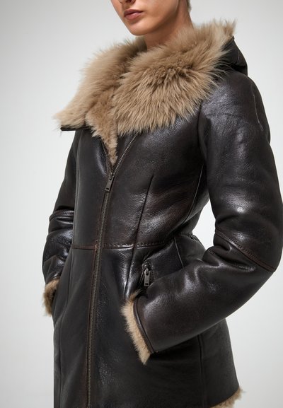 Brūns ādas mētelis ar mākslīgo kažokādu, ar rāvējslēdzēja aizdari un sānu kabatām. Gluda tekstūra ar pieguļošu dizainu.