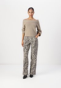Beige off-shoulder ribbed sweater paired with loose, high-waisted leopard print pants. Smooth texture, block-heeled black shoes.