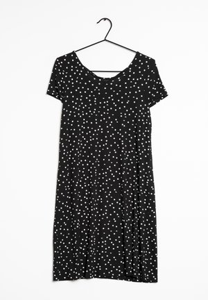 Vestido negro con mangas cortas, que presenta un patrón de pequeños cuadros blancos. Tejido suave y silueta en A. Cuelga de un gancho negro.