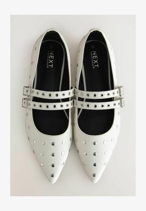 Baltas ādas plakano kurpju modelis ar norādītām pirkstiem, dekorēts ar sudraba kniedēm un divām sprādzēm pāri pēdas daļai. Melns iekšējais oderējums.