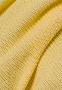 Weiches, gelbes Strickgewebe mit einem strukturierten Muster, das eine feine Webart und einen leichten Glanz aufweist und sanft in Falten fällt.