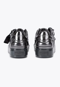 Une paire de baskets métalliques noires brillantes Kurt Geiger London vues de l'arrière avec le logo de la marque sur le talon et la semelle, sur un fond blanc.
