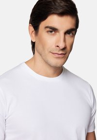 Biała bawełniana koszulka z krótkim rękawem i okrągłym dekoltem, charakteryzująca się gładką fakturą i dopasowanym krojem.