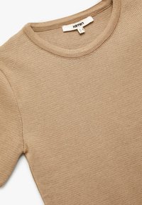 Camiseta de punto corta de manga en color beige con escote redondo. Textura suave y detalles de canalé sutiles. Etiqueta de cuidado visible en el escote.