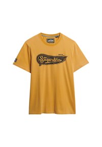 Camiseta de algodón amarilla con mangas cortas, que presenta un logo gráfico negro y un diseño de alas en el pecho; cuello redondo, corte regular.