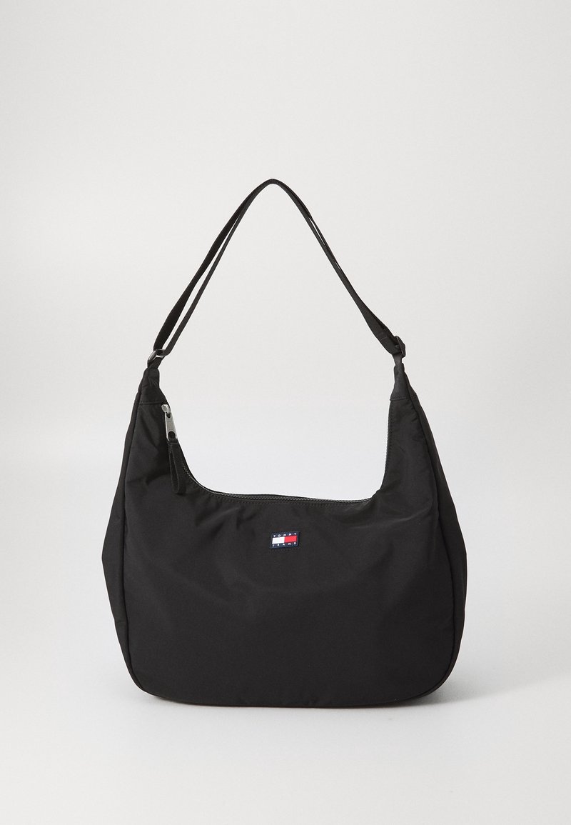 Sac à épaule noir avec une seule bandoulière, fermeture éclair, et petite étiquette logo rectangulaire au centre devant.
