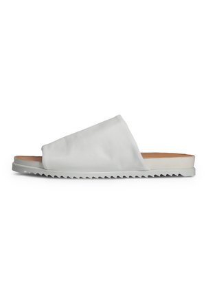 White slip-on sandal with a textured upper, featuring a wide strap and ridged rubber sole for enhanced grip. Simple, minimalist design.