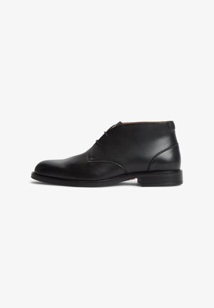 Stivaletto nero in pelle con due occhielli, finitura liscia, tacco basso e punta rotonda, mostrato in profilo laterale su sfondo bianco.