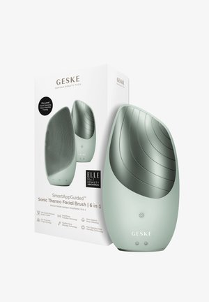 SmartAppGuided Sonic Thermo-Gesichtsreinigungspinsel in sanftem Grün, mit einer strukturierten Silikonoberfläche und einem sanft geschwungenen Design; enthält Verpackungsdetails.