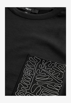 Černé tričko s texturovanou kapsou a stříbrným, spirálovitým vzorem. Vyrobeno z bavlny, má kulatý výstřih a krátké rukávy.