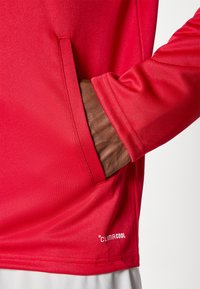 Κόκκινο πουκάμισο με μακριά μανίκια, με υφή υφάσματος, πλαϊνή τσέπη και εμφανές λογότυπο "CLIMACOOL" στο τελείωμα.