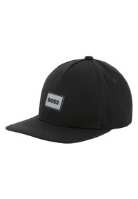 Casquette noire en coton, avec une visière plate, un design structuré et une étiquette blanche rectangulaire avec le mot "BOSS" en noir.