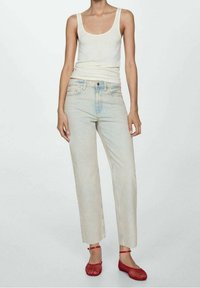 Top blanco sin mangas, vaqueros rectos de un azul claro y zapatillas de malla rojas. Diseño simple, textura suave y ajuste casual. Sin patrones ni detalles metálicos.