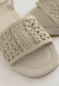 Woven béžové kožené sandály na klínku s texturovaným popruhem, hladkou podrážkou a jemným prošíváním kolem okrajů pro zvýraznění detailu.