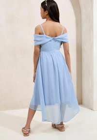 Robe en chiffon bleu clair avec des manches dénudées, une taille cintrée et un ourlet fluide. Fermée par un zip dans le dos, à associer avec des sandales.
