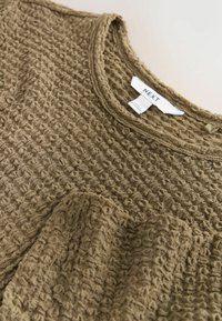 Olivgrüner, strukturiertes Sweatshirt mit Waffelstrick-Muster, Rundhalsausschnitt und weichem, lässigem Stoff. Markenetikett innen am Kragen sichtbar.