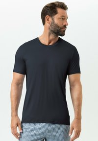 T-shirt bleu foncé à manches courtes en tissu lisse et léger avec un col rond, associé à un short de bain à motifs.