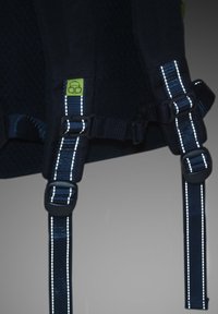 Čierny látkový batoh s popruhmi na rameno so reflexnými pruhmi, nastaviteľnými prackami a malým zeleným logom. Textúrovaný povrch s bezpečnostnými kovovými časťami.