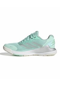 Baskets basses Adidas vert clair avec lacets, dessus en mesh, bandes argentées et semelle blanche, conçues pour le sport et les activités en plein air.