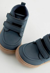 Ciemnoniebieskie buty z dwoma rzepami, wykonane z gładkiej skóry, z wyściełanym kołnierzem i jasnobrązową gumową podeszwą.
