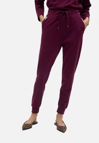 Joggers burdeos con cintura ajustable, bolsillos laterales y puños elásticos. Combinados con bailarinas de charol con estampado de leopardo.