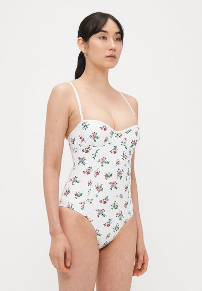 Costume da bagno bianco con stampa floreale, caratterizzato da spalline sottili, corpetto strutturato e gambe ad altezza elevata. Texture liscia e copertura moderata.
