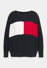 Schwarzer Pullover mit strukturiertem Oberteil, ausgestattet mit einem auffälligen horizontalen Design und roten sowie weißen Paneelen auf der Brust, und einem lockeren Schnitt.