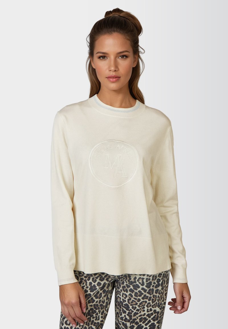 Cream-colored sweater with a round neckline, embroidered logo on the front, and ribbed hem. The sleeves are long and fitted.