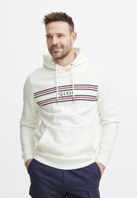 Sudadera blanca con un diseño de rayas horizontales en rojo y negro, con un bolsillo tipo canguro y capucha ajustable con cordón.