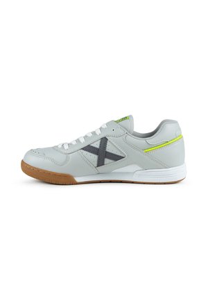 Baskets gris clair avec des lacets blancs, logo "X" gris foncé sur le côté, accent jaune fluo sur le talon et semelle marron clair.