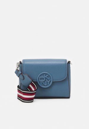 Blauwe leren crossbodytas met rond DKNY-logo op de voorflap en afneembare zwart-wit-rode gestreepte stoffen schouderriem.