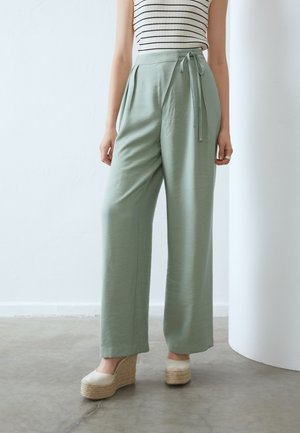 Lys grønne vidde bukser med bindebånd i taljen, lavet af blødt stof. Kombineret med cremede espadrille wedges for et afslappet look.