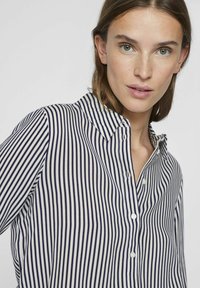 Striped button-up shirt in navy and white, featuring a collar and subtle texture, with small white buttons down the front.