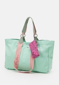 Mintgrüner Taschenbeutel mit pinken und grünen Trägern, der eine kleine Tasche mit pinkem Leopardenmuster enthält, aus strapazierfähigem Stoff gefertigt.