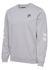 Felpa grigia chiara a maniche lunghe con polsini e orlo a costine, presenta il logo hummel in nero, bianco e beige sul petto e chevron bianchi sulle maniche.