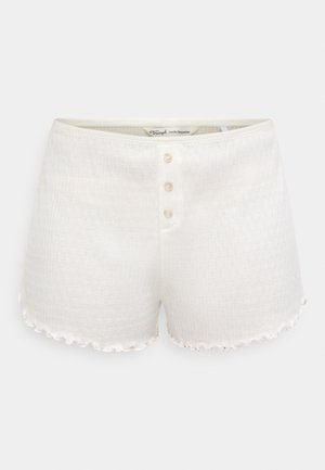 Baltas kokvilnas šortus ar fakturētu rakstu, kuriem ir pogas priekšpusē ar trim apaļām pogām un krokotu apakšmalas apdare.