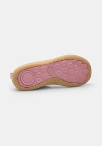 Suela de zapato con diseño de goma flexible. La parte interior rosa presenta círculos elevados para mayor agarre, rodeados por una capa exterior color beige. Acento circular cerca del talón.