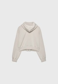 Sudadera corta en beige claro, con capucha ajustable, mangas largas, puños y dobladillo acanalados, y una textura suave y lisa.