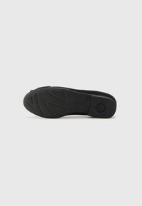 Semelle d'une chaussure noire avec motifs de bande de roulement, talon légèrement surélevé et nom de marque « Gabor » embossé près de la voûte plantaire.