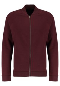 Sudadera con cremallera color marrón burdeos, con cuello alzado, puños acanalados y dobladillo. Fabricada en un tejido suave y liso con un diseño sin costuras. Sin bolsillos visibles.
