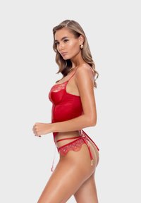 Czerwony satynowy zestaw bielizny z koronkowymi wykończeniami, regulowanymi ramiączkami i detalami w postaci podwiązek. Gładka tekstura i misternie wykonane wzory dodają wizualnego zainteresowania.